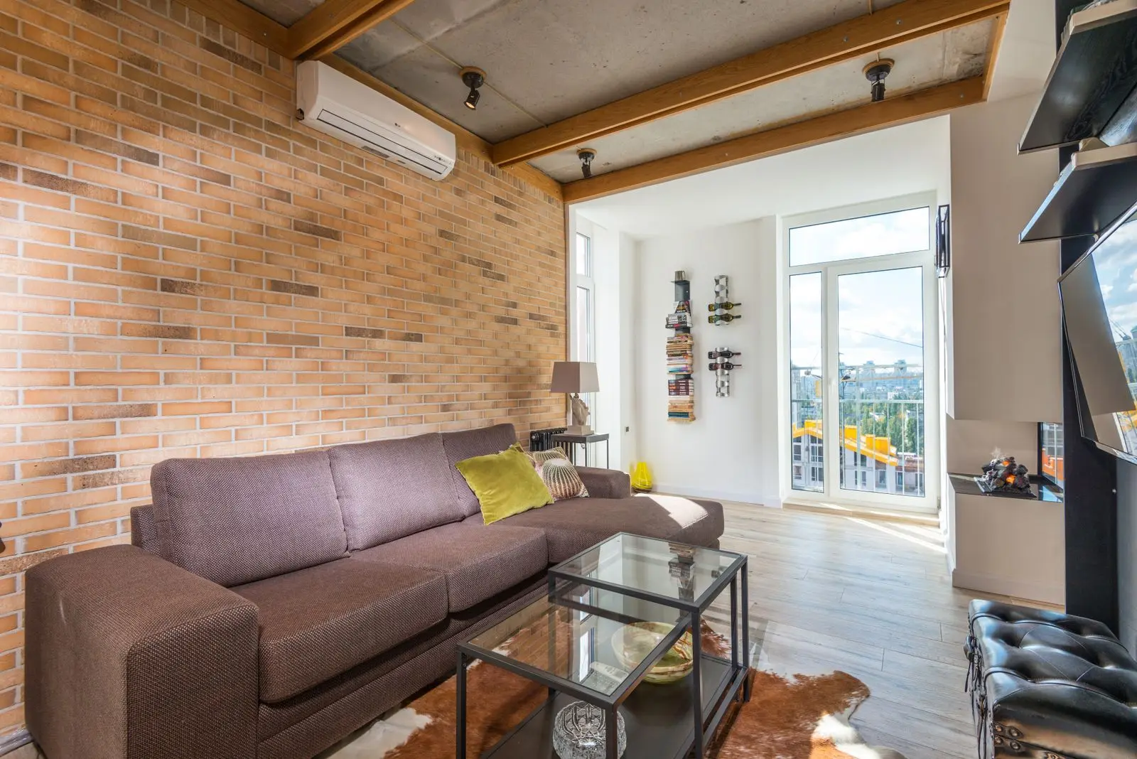 A bright living room with a ductless indoor unit mounted high on a brick wall